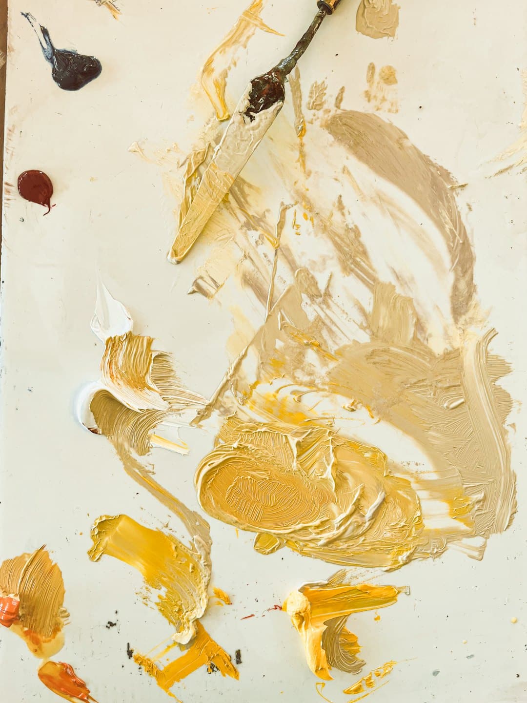 Tavolozza di un artista con gialli, marroni, blu e rossi colori a olio e spatola.