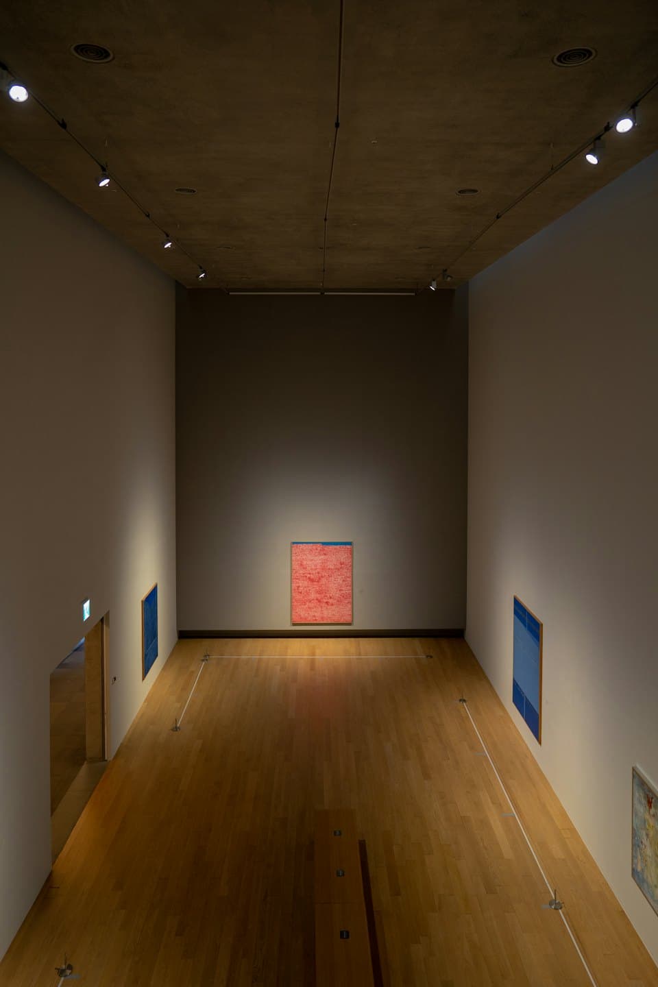Tre quadri astratti sono appesi alle pareti di una galleria.