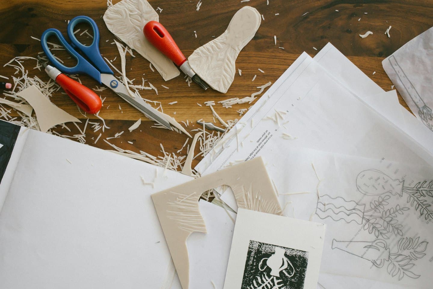 Strumenti e materiali per la stampa linoleografica su un tavolo di legno.