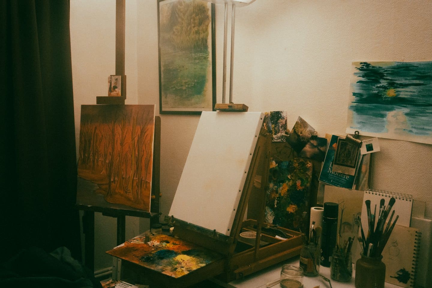 Scrivania in uno studio d'arte con dipinti, pennelli e tavolozza.