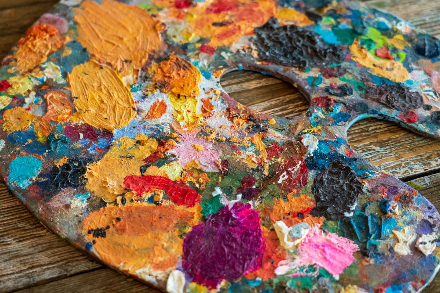 Tavolozza di un artista con colori ad olio vivaci su un tavolo di legno.