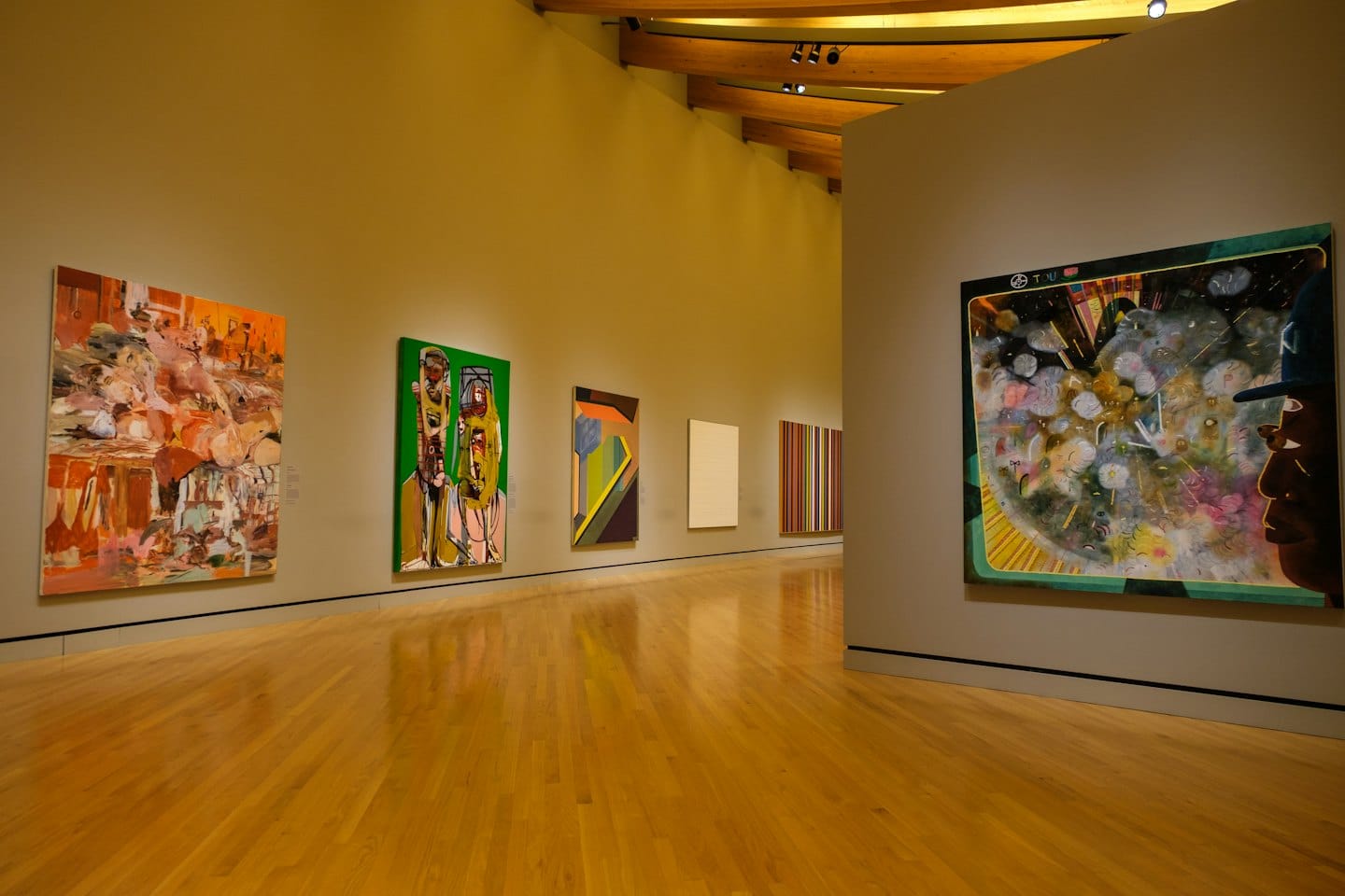 Dipinti astratti e figurativi sono appesi alle pareti della galleria.
